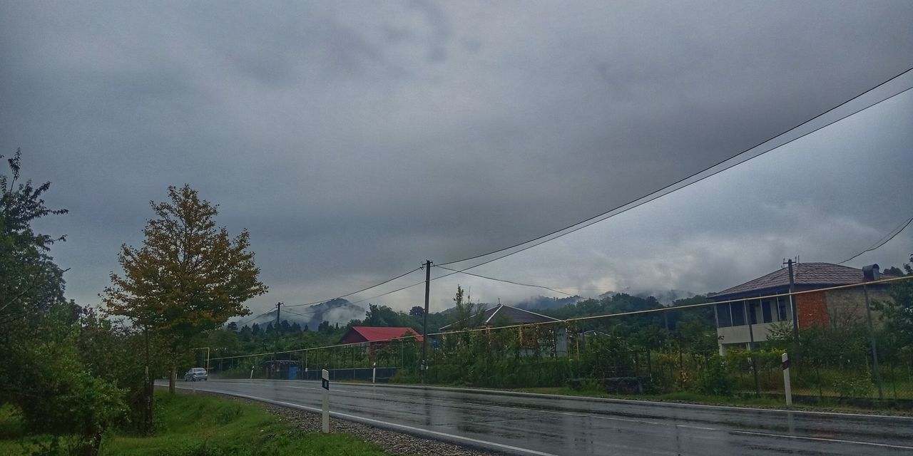 RAILROAD TRACKS BY ROAD AGAINST SKY