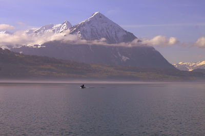 Scenic view of sea and snowcapped mountains against sky