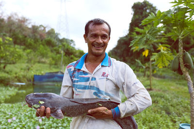 Portrait of smiling man standing against trees