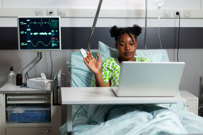 Woman using laptop while sitting at hospital