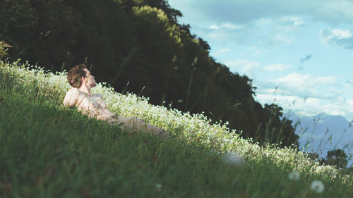 Shirtless young man lying on grassy field