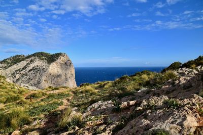 Rock formations by sea against blue sky