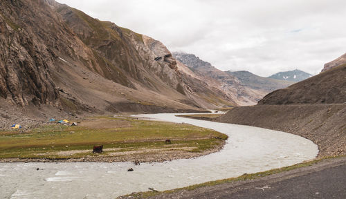 Scenic view of road by mountains against sky