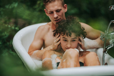 Midsection of shirtless man with woman in bathtub