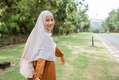 Portrait of young woman standing against trees