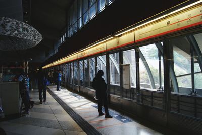 Rear view of people walking on railroad station platform