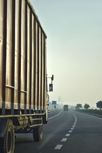 Vehicles on road against clear sky