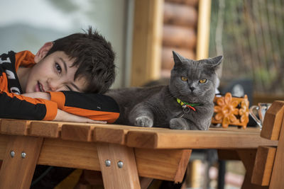 Portrait of boy with cat on table