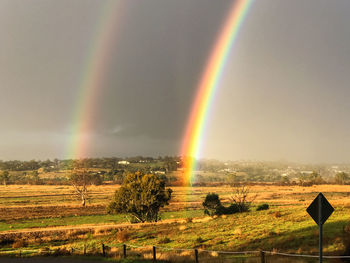 Scenic view of rainbow over field against sky