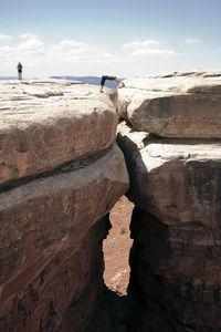 People on mountain against sky during sunny day at canyonlands national park