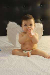 Cute baby girl sitting on sofa at home