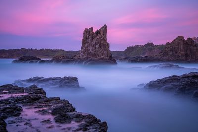 Rock formations by sea against sky during sunset