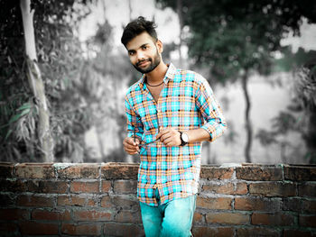 Portrait of young man standing against wall