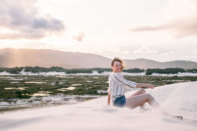 Portrait of smiling young woman on beach against sky