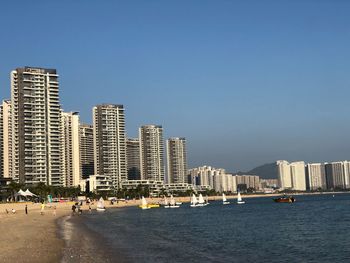 Modern buildings by sea against clear sky