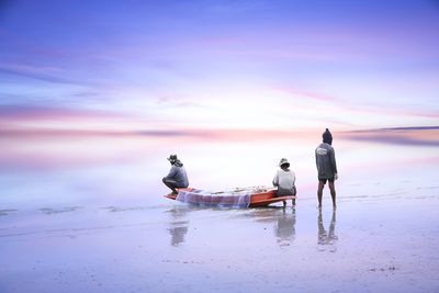 People on beach against sky during sunset