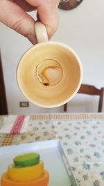Midsection of person holding coffee cup on table