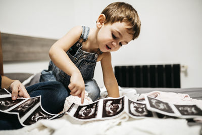 Little boy looking at ultrasound scans of his pregnant mother