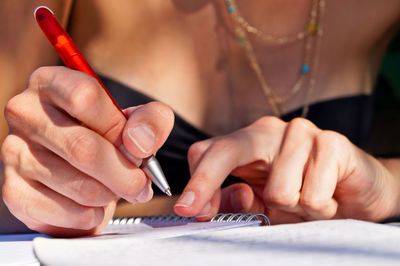 Midsection of woman writing on note pad