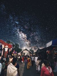 People at market against sky at night