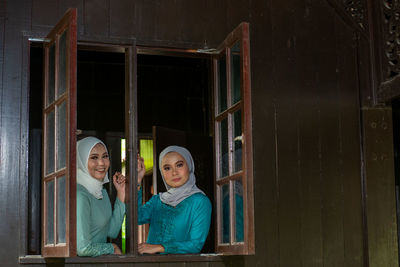 Portrait of two muslim women by the window in a malay wooden house. 