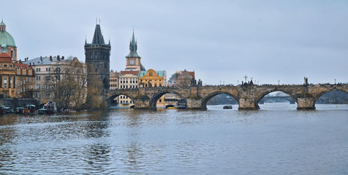 Arch bridge over river against buildings in city