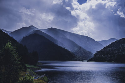 Scenic view of river and mountains against sky