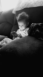 Close-up of boy sitting on sofa at home