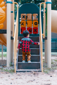 Rear view of boy playing on steps in playground