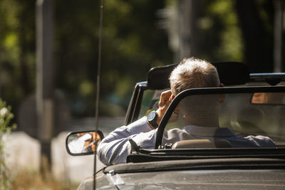 Rear view of man sitting on car