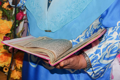 Midsection of woman reading koran