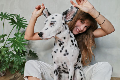 Portrait of woman with dog against white wall