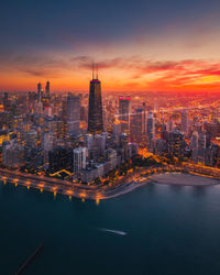 Illuminated buildings in city against sky during sunset