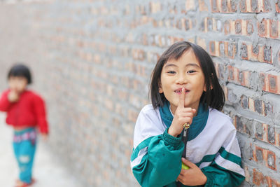 Vietnamese little girls finger up to lips for making a quiet gesture on the road