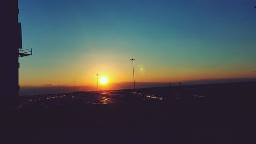 Silhouette cars on road against clear sky during sunset