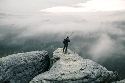 Rear view of man on rock against sky