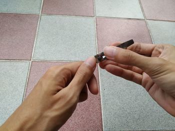 Midsection of man holding hands on tiled floor