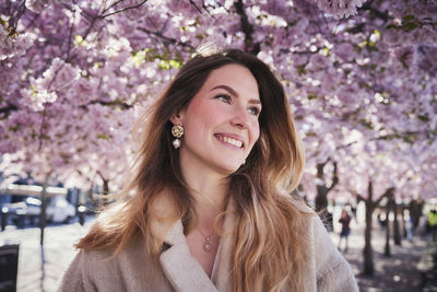 Young woman standing under cherry blossom