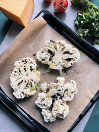 Delicious cauliflower steaks on baking sheet and tomato, cheese