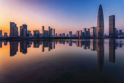 Reflection of buildings in city at sunset