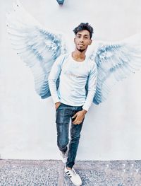 Portrait of young man standing against wall