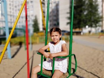 Portrait of cute girl sitting on swing at playground