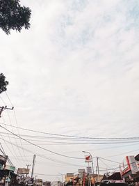 Low angle view of electricity pylon in city against sky