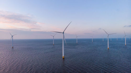Wind turbines in sea against sky during sunset, windmill turbines in the netherlands 