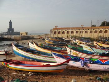 Boats moored on shore in city against sky