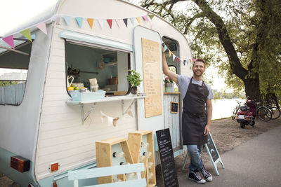 Portrait of confident male owner standing outside food truck on street