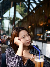 Portrait of young woman drinking glass in restaurant