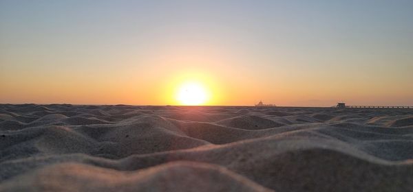 Scenic view of beach against clear sky during sunset