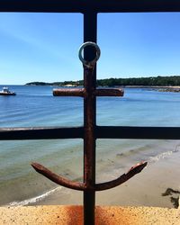 Close-up of metallic structure on beach against sky