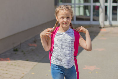 Cute girl with the inscription  paris on the t-shirt with a backpack behind his back